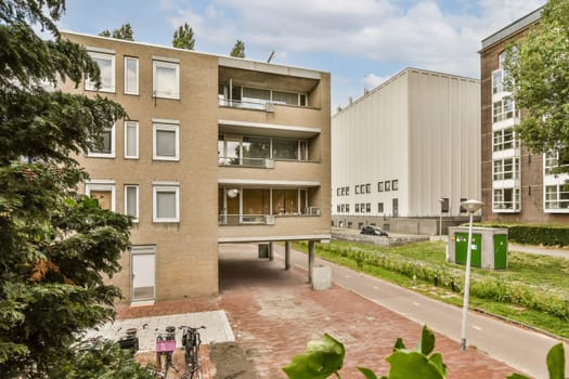 an outside view of a building with trees in the fore, and people walking on the sidewalk next to it