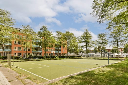 an outdoor tennis court with trees and grass in the foregrounding area at park view apartments, south london