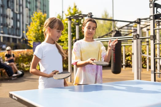 Cute girls playing ping-pong indoors. High quality photo