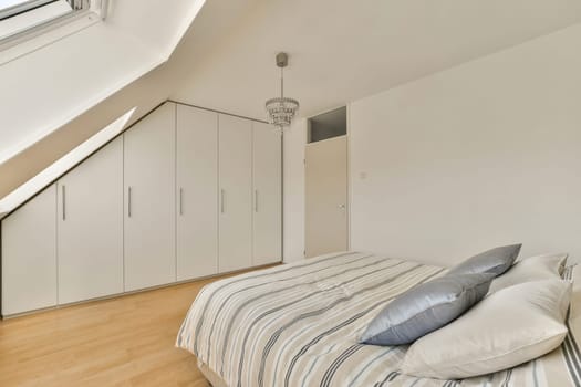 a bedroom with a bed and cupboards on the wall in front of the bed is an attic style loft