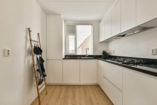 a kitchen with white cabinets and black counter tops on the counters in front of the sink is wooden flooring