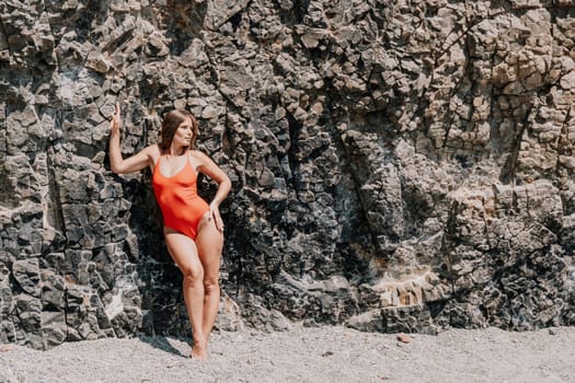 Side view a Young beautiful sensual woman in a mint long dress posing on a volcanic rock high above the sea during sunset. Girl on the nature on overcast sky background. Fashion photo