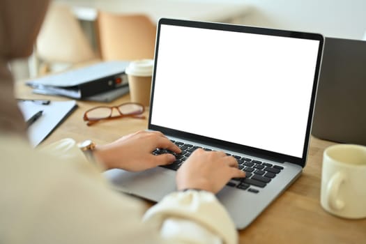 Over shoulder view of female employee hands typing on laptop. Business and technology concept.