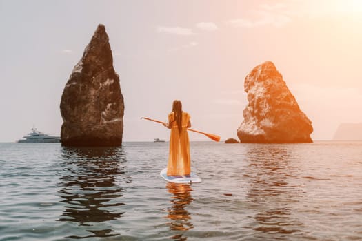 Close up shot of beautiful young caucasian woman with black hair and freckles looking at camera and smiling. Cute woman portrait in a pink bikini posing on a volcanic rock high above the sea