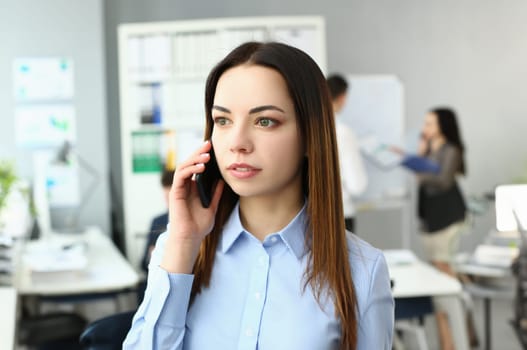 Portrait of smart lady using modern gadget to talk with witty colleagues on big distances. Gorgeous young manager discussing questionable business topic. Company meeting concept