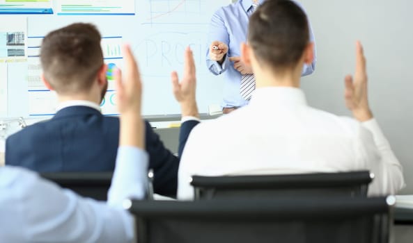 Focus on hand pointing to person wanting to ask something. Workers sitting at office in conference room. Company and business meeting concept. Blurred background