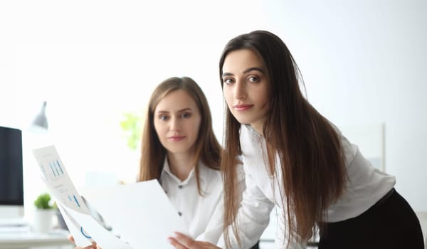 Portrait of joyful businesswoman looking at camera with joy and holding important business document with significant corporation charts and graphs. Accounting office concept