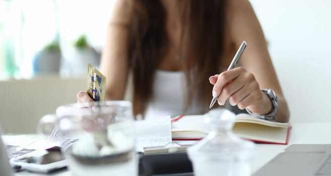 Focus on tender businesswoman arms writing with metallic pen and holding important numbers in significant charts and graphs. Biz concept. Blurred background
