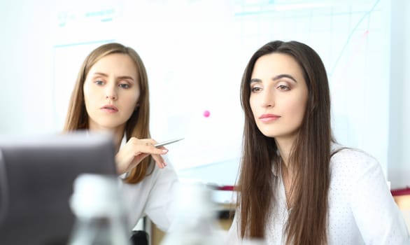 Portrait of smart businesswoman sitting at comfortable workplace and looking at something with concentration. Business partner discussing project. Accounting office concept