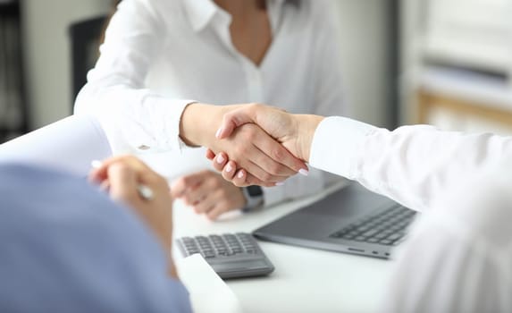 Focus on women shaking hands after signing profitable bargain. Business negotiations concept. Biz making good contract between partners. Blurred background