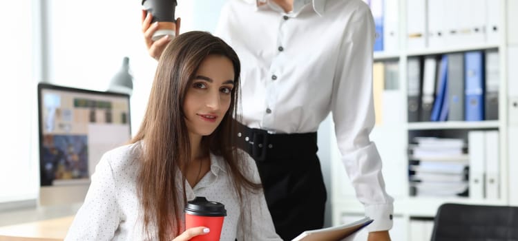 Portrait of cute businesswoman sitting in modern workplace with friendly colleague and working on important business project. Accounting office concept