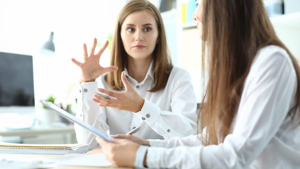 Portrait of concerned businesswoman sitting in modern workplace and discussing important topic. Pretty business lady working on project. Accounting office concept