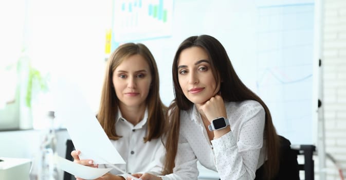 Portrait of smart businesswoman wearing high-tech digital watches and looking at camera with calmness and self-satisfaction. Accounting office concept