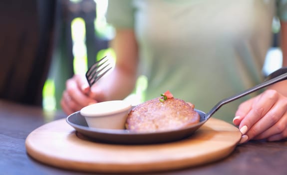 Potato pancakes with pancakes with sour cream in frying pan stands on table in front of guest in cafe. Cooking delicious potato dishes concept