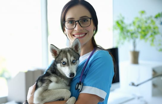 Young smiling veterinarian holds dog in arms. Veterinary medical services concept