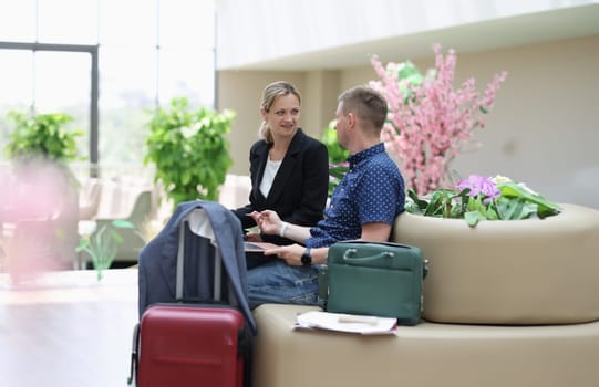 Man and woman in business suits talking and waiting for plane at airport. Business trips abroad concept