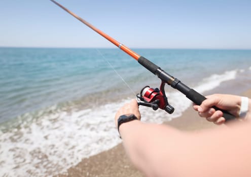 Man fishing with rod on seashore closeup. Men hobby fishing concept