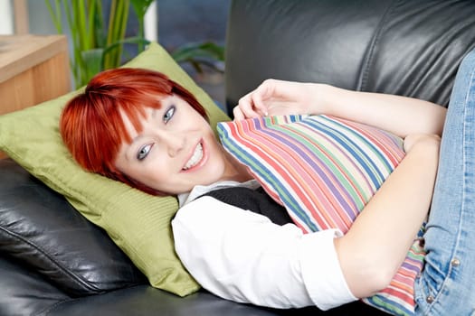 Young female lying on a sofa and relaxing in her living room.