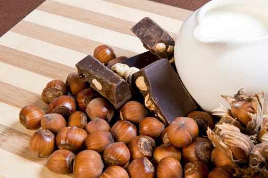 milk, hazelnuts and hazelnut chocolate on cutting board bamboo