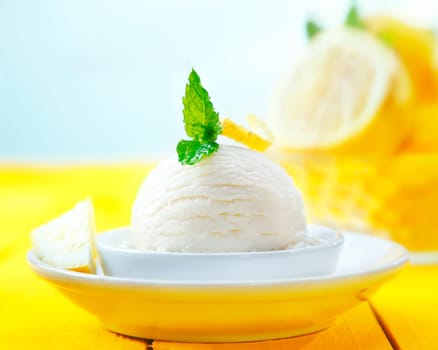 Scoop of tangy refreshing lemon sorbet icecream served for dessert on a yellow wooden table
