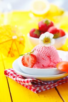 Enjoying a serving of fresh strawberry icecream on a yellow tabletop poolside in summer