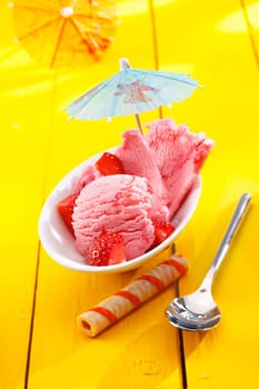 Serving of creamy strawberry icecream and diced ripe strawberries served with a cocktail umbrella on a tropical vacation. For ice-cream concept look at my portfolio