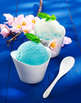 Refreshing blue individual servings of Italian icecream in decorative boat-shaped bowls with a twig of pink spring blossom
