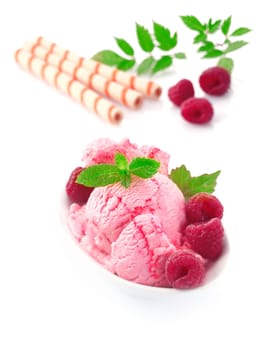 Fresh whole ripe raspberries and icecream dessert garnished with leaves of mint served on a white background