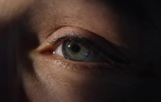 Closeup of woman green eye in dark. Slit lamp examination concept
