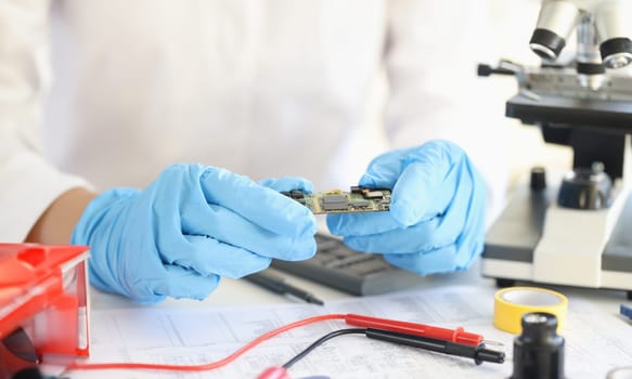 Scientists holding microchip in rubber gloves in laboratory closeup. Invention of new electronic technologies concept