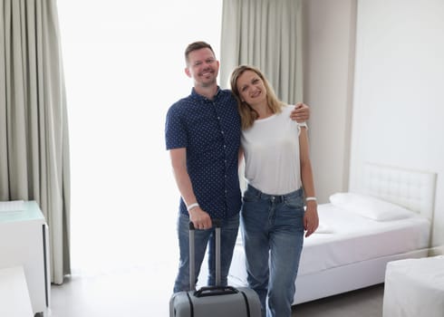 Young couple standing with suitcase in hotel room. Honeymoon concept