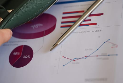 Man putting ballpoint pen and documents with charts in leather bag closeup. Remote business meeting concept