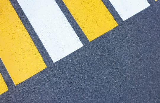 Closeup of yellow and white stripes on gray asphalt background. Traffic laws concept