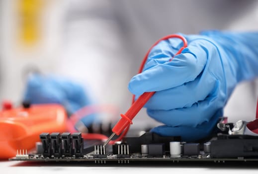 Master repairer testing motherboard with feeler gauge closeup. Repair and maintenance of computer equipment and electronics concept
