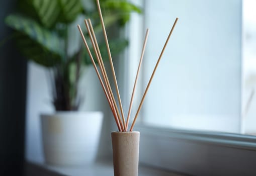 Wooden stick standing in jar with aromatic oils in apartment closeup. Sale of air fresheners concept