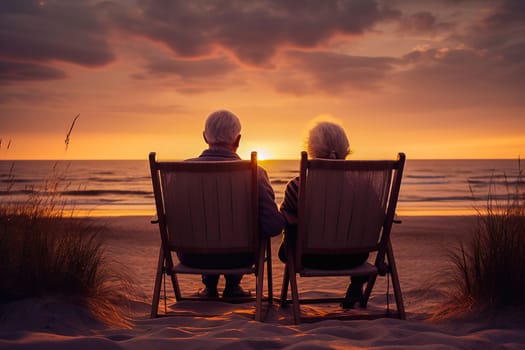 Happy retired couple relaxing on sun loungers near the seashore at sunset. High quality photo