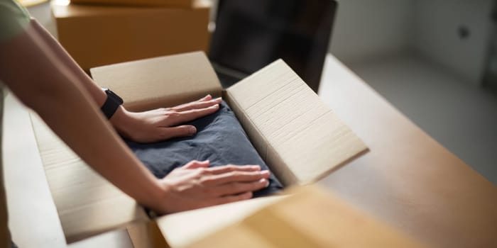 Close up young woman seller prepare parcel box of product for deliver to customer. Online selling, ecommerce. Young woman working online ecommerce shopping at her shop.