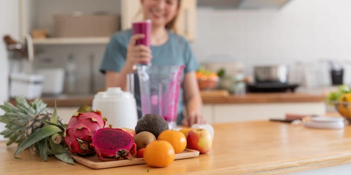 Beauty healthy asian woman making fruit smoothie with blender. woman drinking glass of fruit smoothie in kitchen. Diet concept. healthy drink.