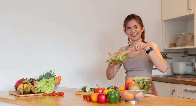Young woman standing in the kitchen making a salad for health.