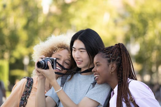 Smiling multi ethnic group of tourist friends checking the photos they have taken during their trip.