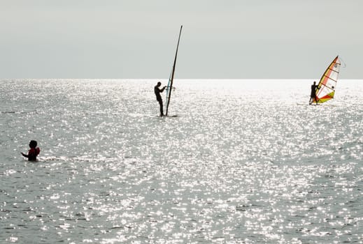 Two surfers practicing on the Baltic Sea,a bather