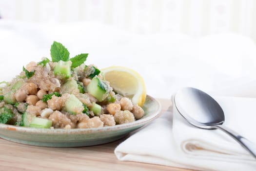 Healthy amaranth grain prepared tabbouleh style with chickpeas, and a lemon wedge