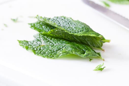 Mint leaves on cutting board with knife out of focus in the background