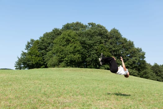 Somersault in nature,young man doing sports training