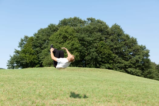 Somersault in nature,young man doing sports training