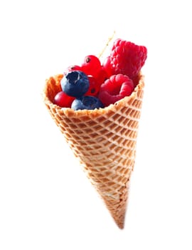 Ice cream Cone filled with fresh bilberries, raspberries and red currants isolated on white background.