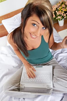 Young woman sitting in bed with a laptop