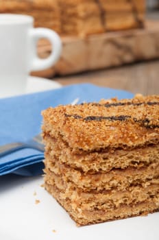Traditional Honey Cake on Plate and White Cup of Coffee on Table