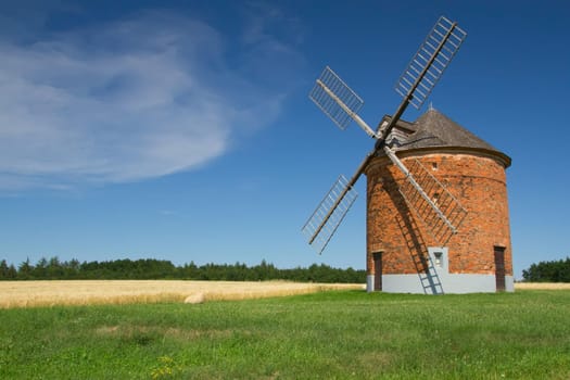 Brick windmill in a field of corn. Blue sky in the background. (Chvalkovice, Czech Republic)