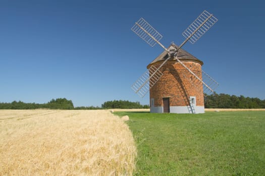 Brick windmill in a field of corn. Blue sky in the background. (Chvalkovice, Czech Republic)